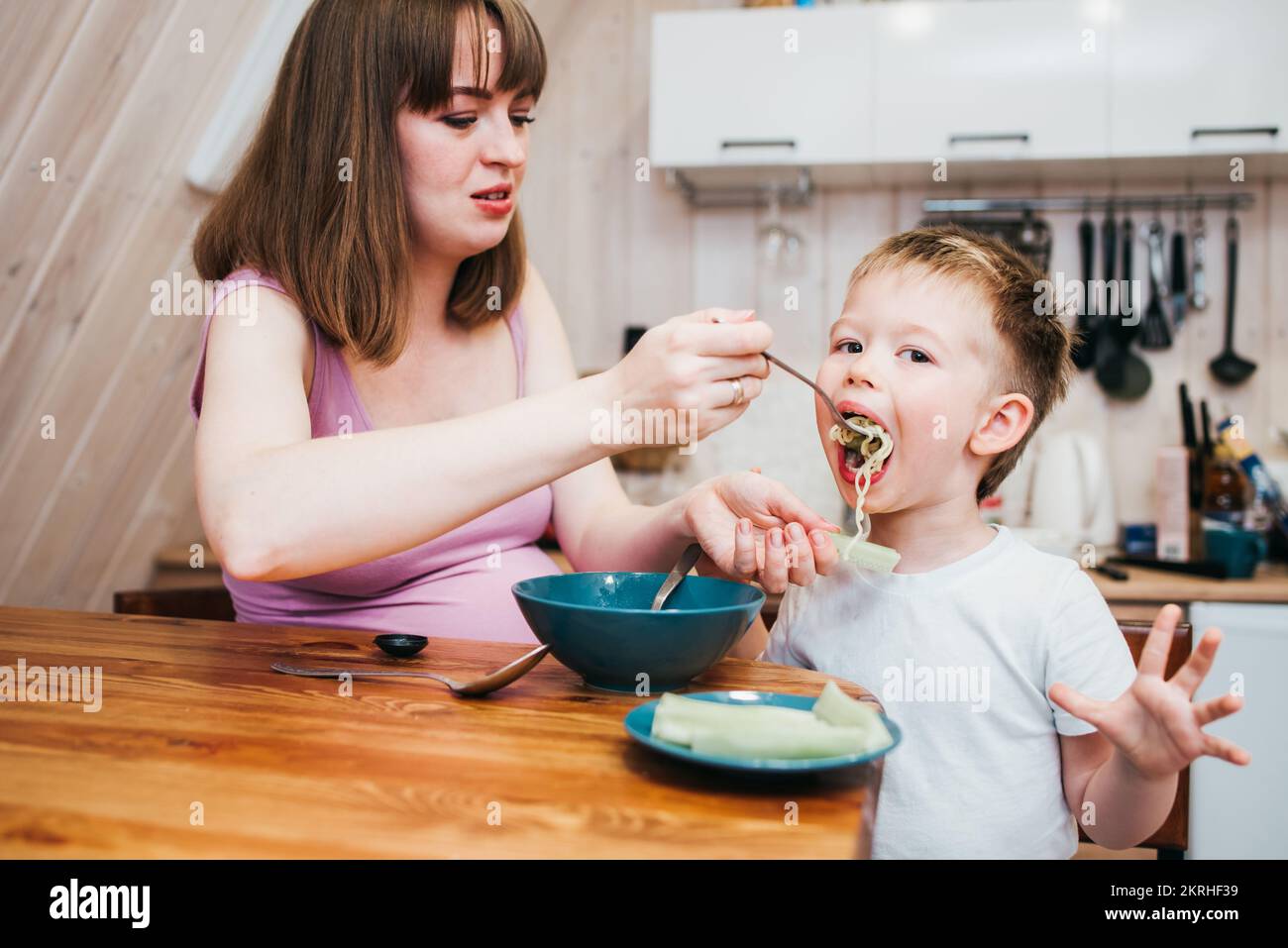 Cheerful little child eats in the kitchen with mom Stock Photo Alamy