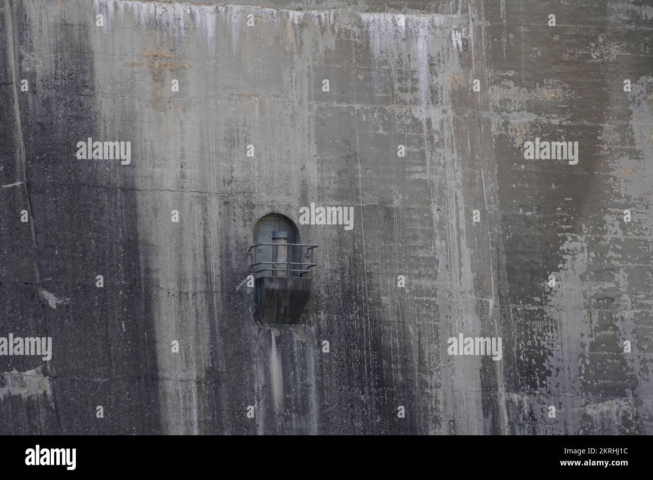 View on huge grey concrete wall of Gigerwald Dam with entrance door. Stock Photo