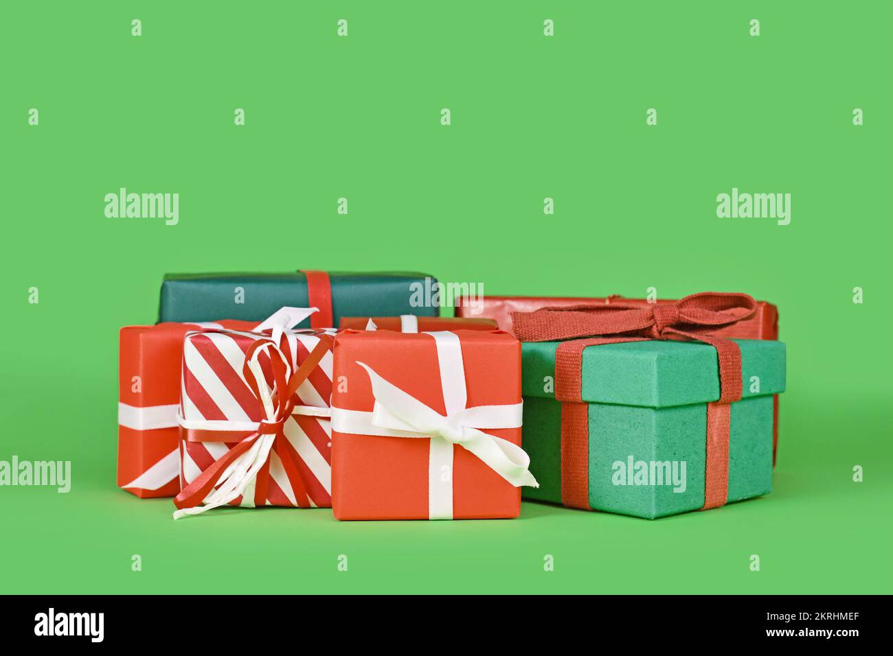 Various small Christmas gift boxes on green background with copy space Stock Photo
