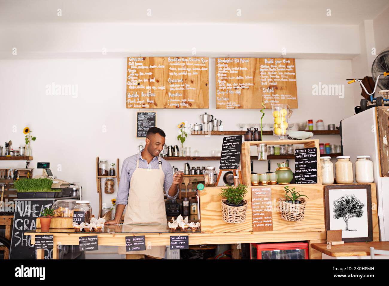 The confirmation text for his coffee bean delivery came through. young barista using a phone at a cafe. Stock Photo