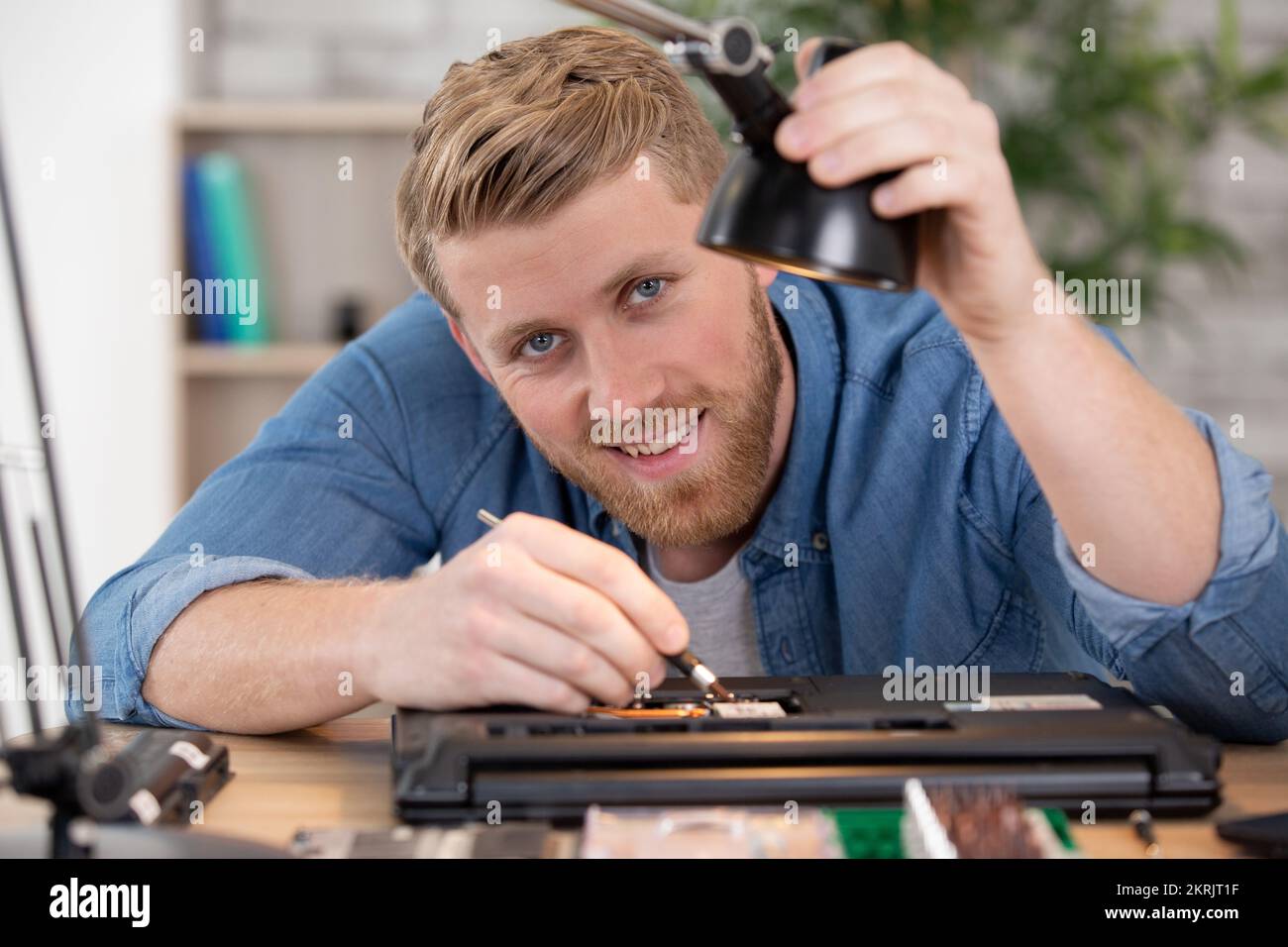 young technician working on broken computer in his office Stock Photo