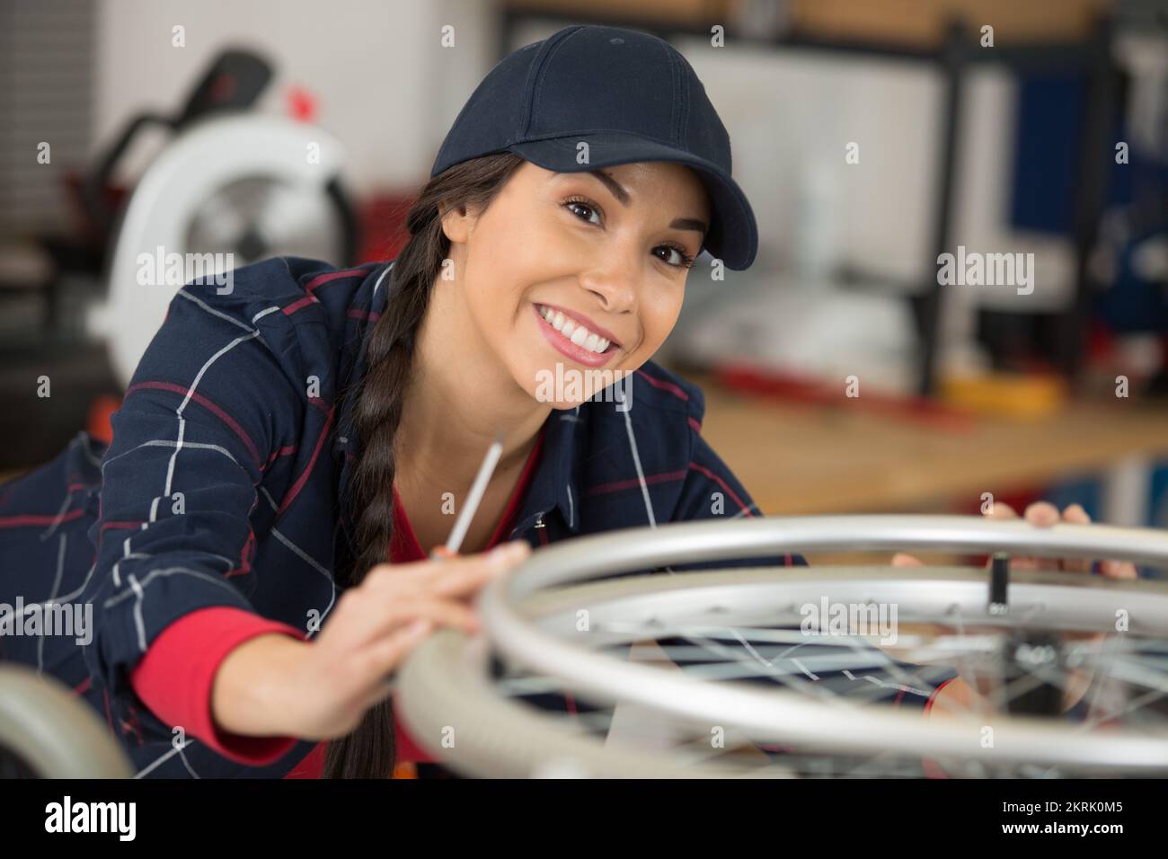 mechanic servicewoman adjusting bicycle wheel in workshop Stock Photo