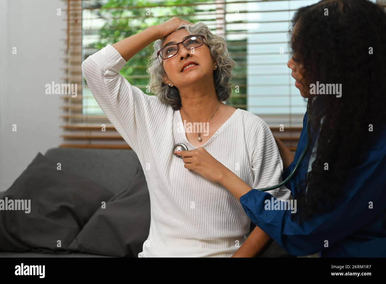 Image of health visitor examining senior female patient during home