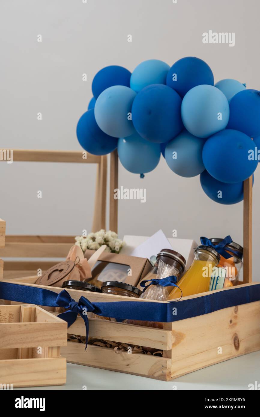 Creative wooden gift box with glass bottles of juices and jars of foods decorated with blue