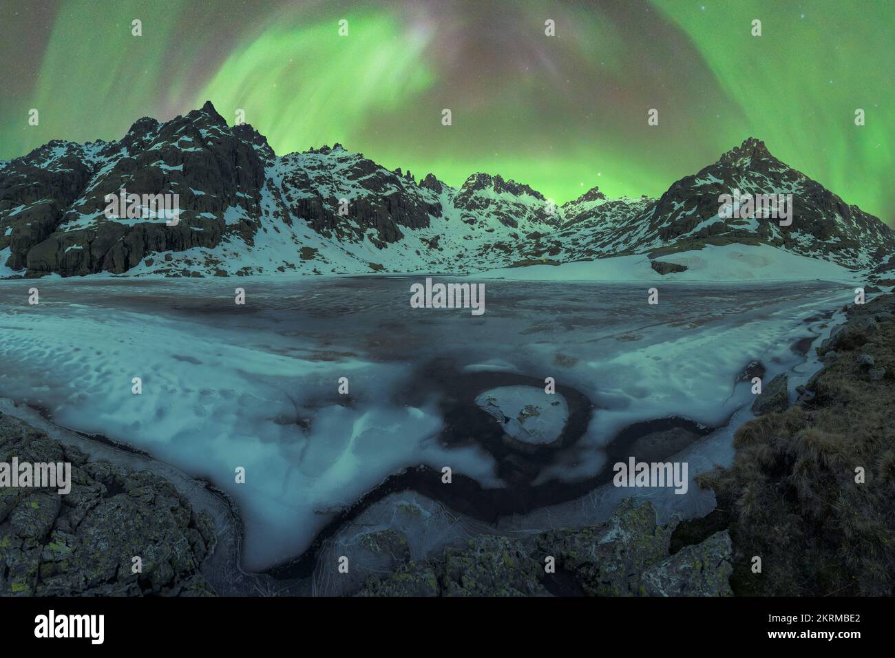 Majestic Aurora Borealis shining over snowy mountains near frozen lake ...