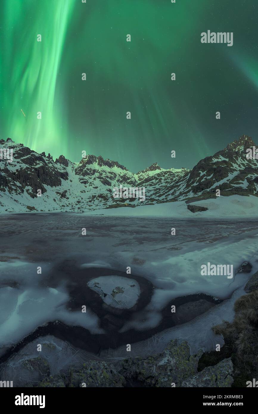Majestic Aurora Borealis shining over snowy mountains near frozen lake ...