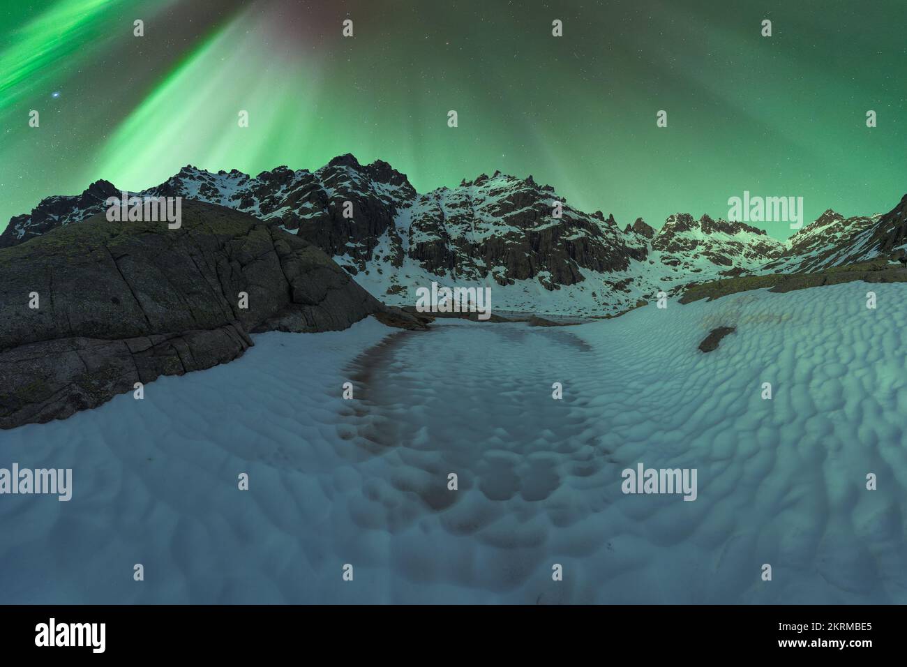 Majestic Aurora Borealis shining over snowy mountains near ground ...