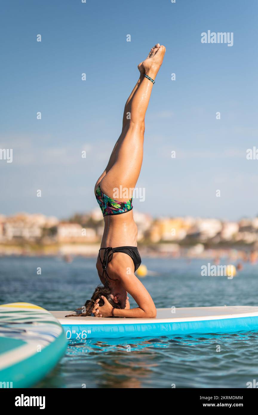 Side view of full body female performing yoga on paddleboard on
