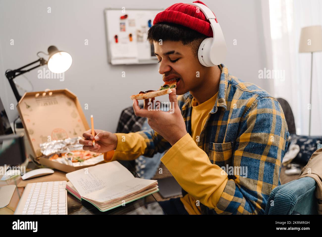 Middle-eastern teenage boy eating pizza while studying at home by ...