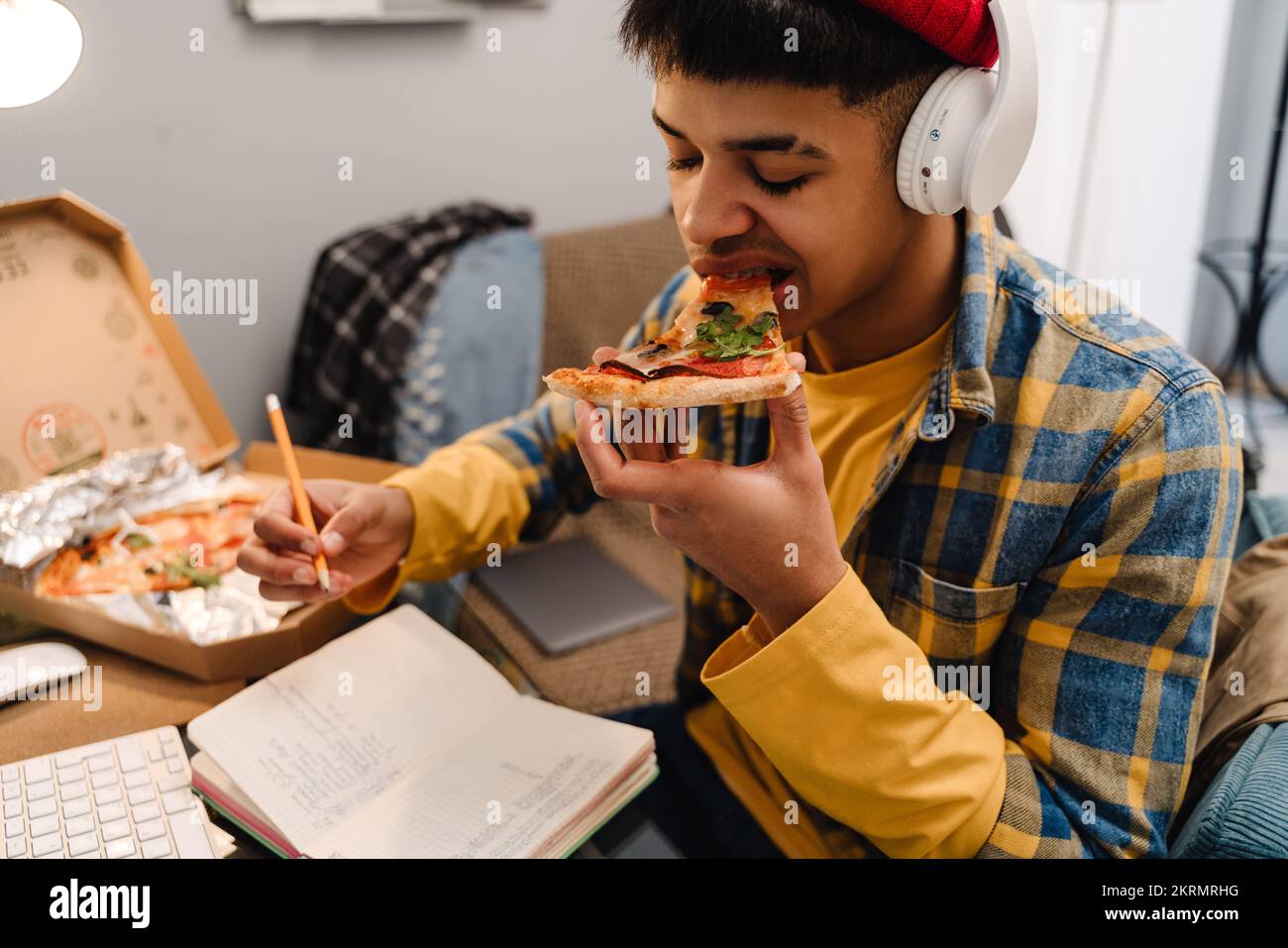 Middle-eastern teenage boy eating pizza while studying at home by ...