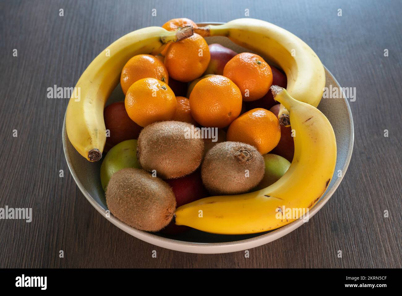 A bowl of mixed citrus fruits, apples, satsumas, kiwi fruit & bananas