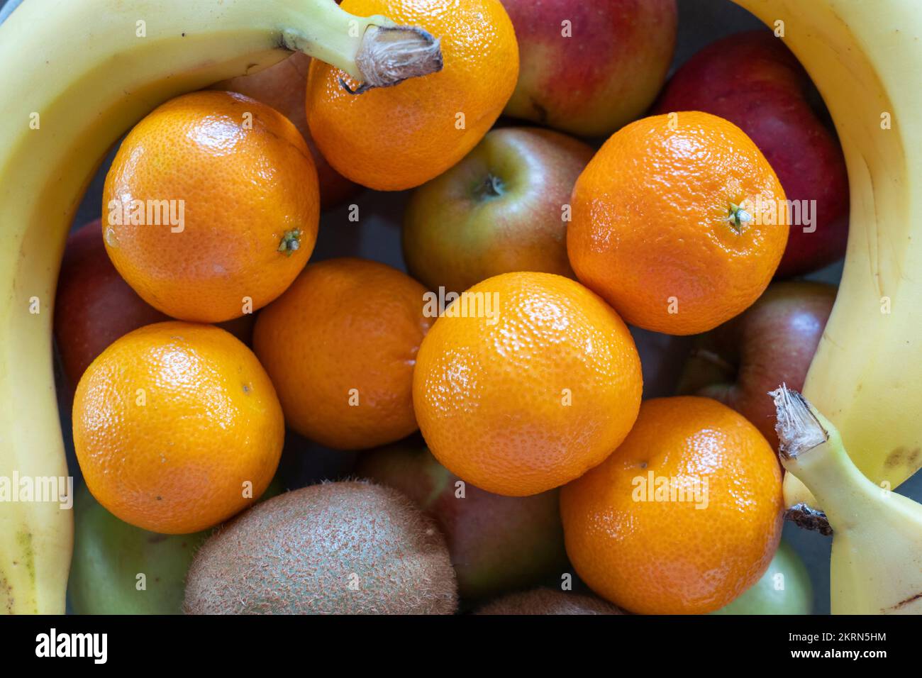A bowl of mixed citrus fruits, apples, satsumas, kiwi fruit & bananas