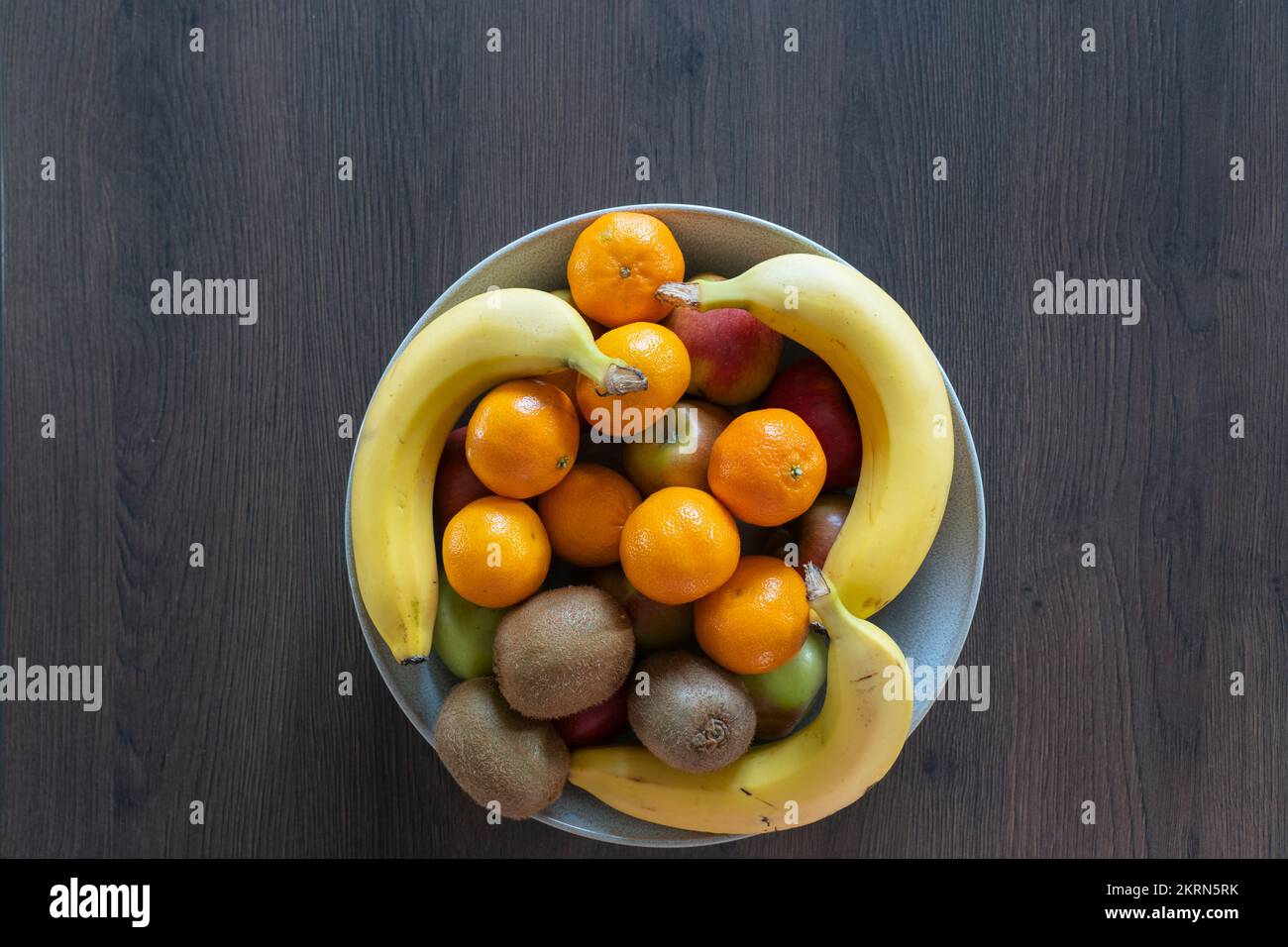 A bowl of mixed citrus fruits, apples, satsumas, kiwi fruit & bananas