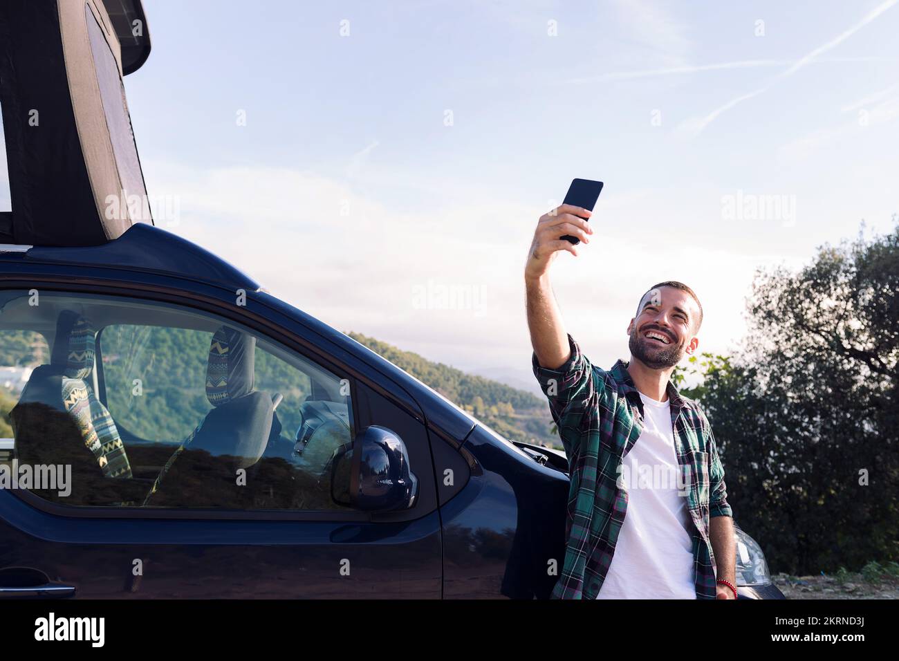 man taking a selfie leaning on his camper van Stock Photo