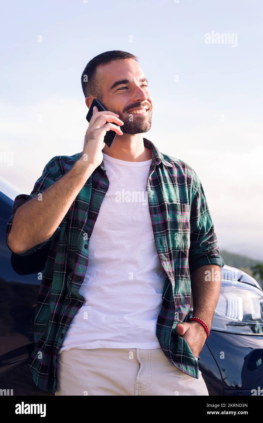 man talking on mobile phone leaning on his camper Stock Photo