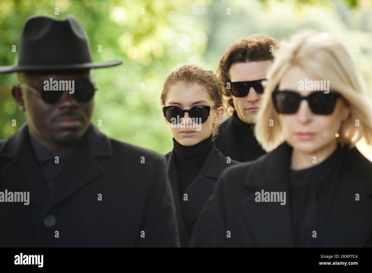 Group of people wearing all black with sunglasses standing in silence