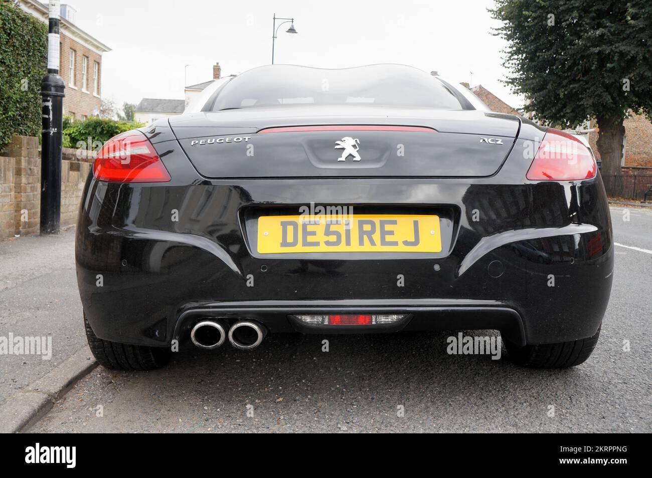 back view of a black Peugeot coupe sports car with DESIRE reg. plate. Stock Photo