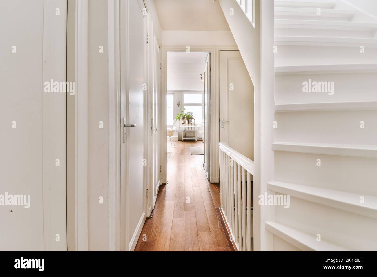 White hallway with wooden stairway leading to second floor of modern ...