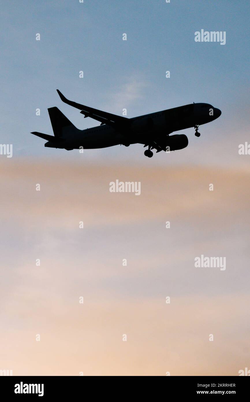 Silhouette of airplane in the sky at sunset with dramatic clouds and copy space Stock Photo