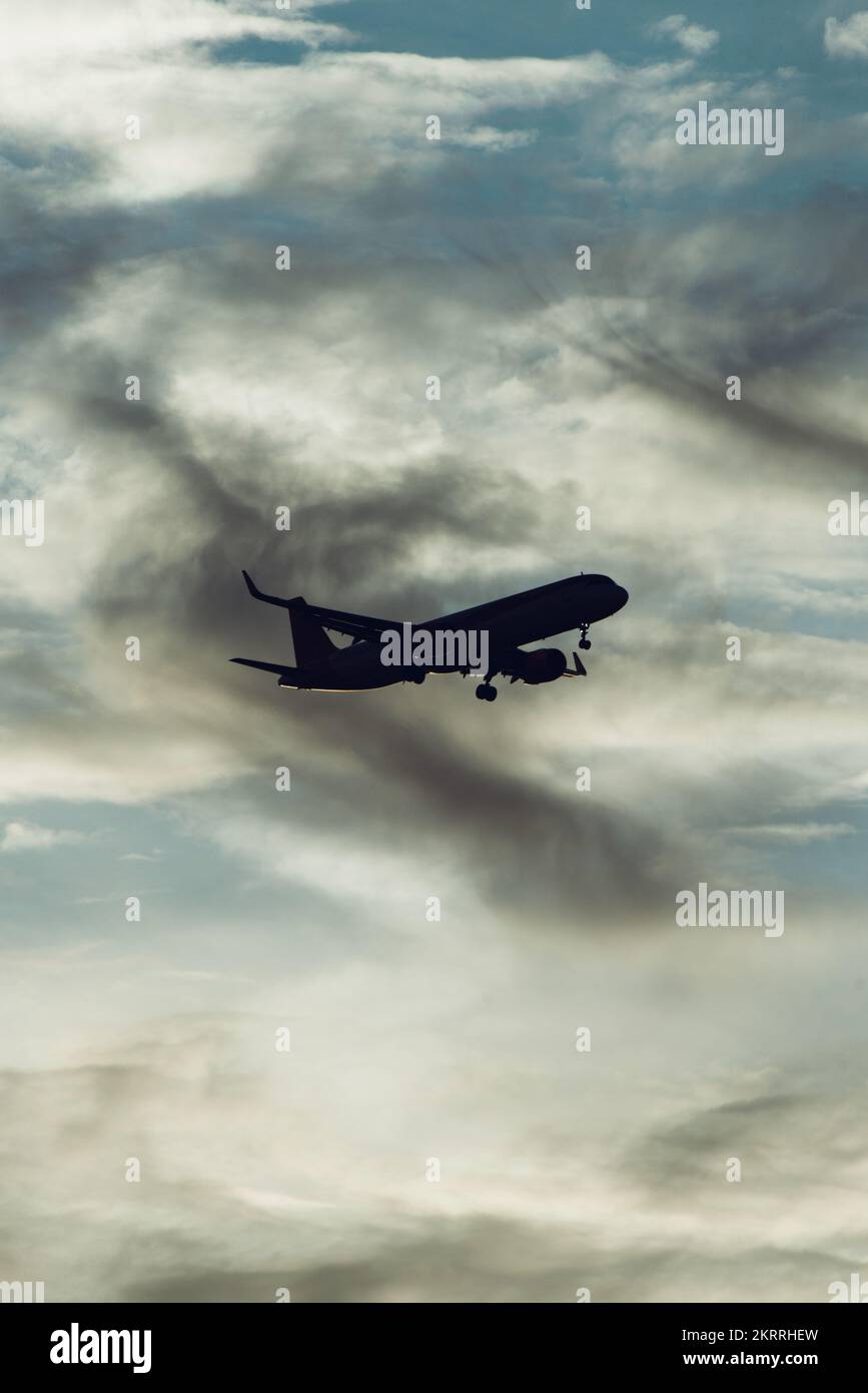 Silhouette of airplane in the sky at sunset with dramatic clouds Stock Photo