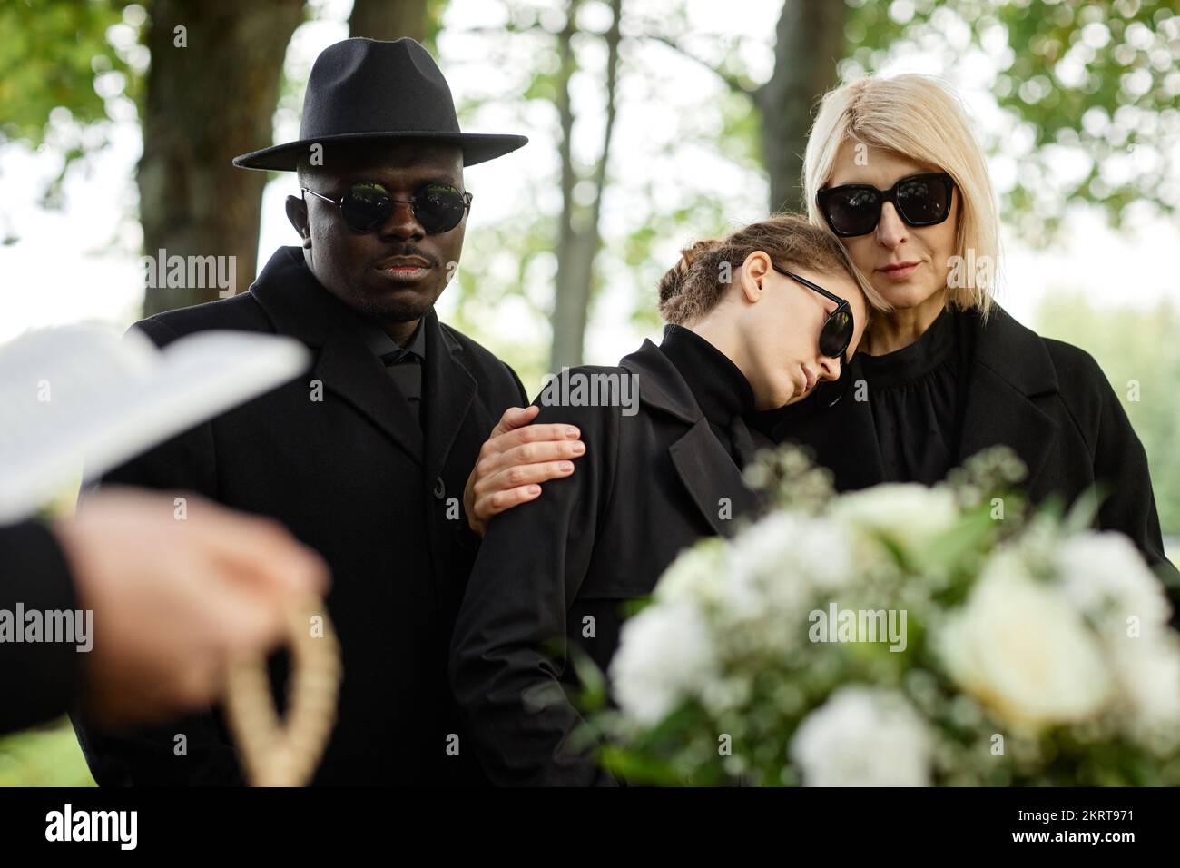 Portrait of mother and daughter embracing at outdoor funeral ceremony