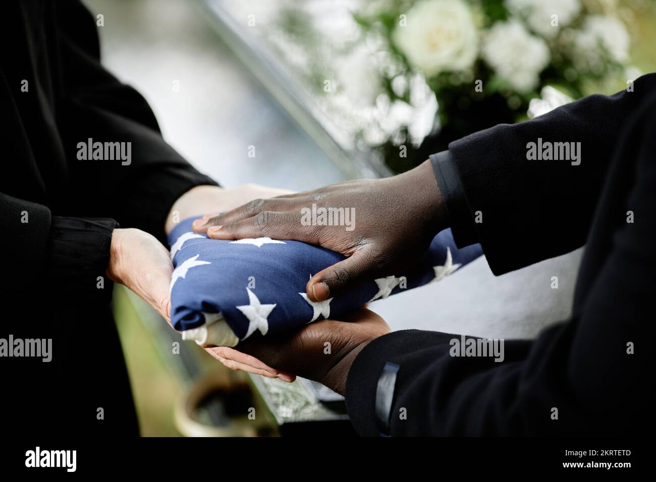 Close up of general handing folded American flag to woman at funeral