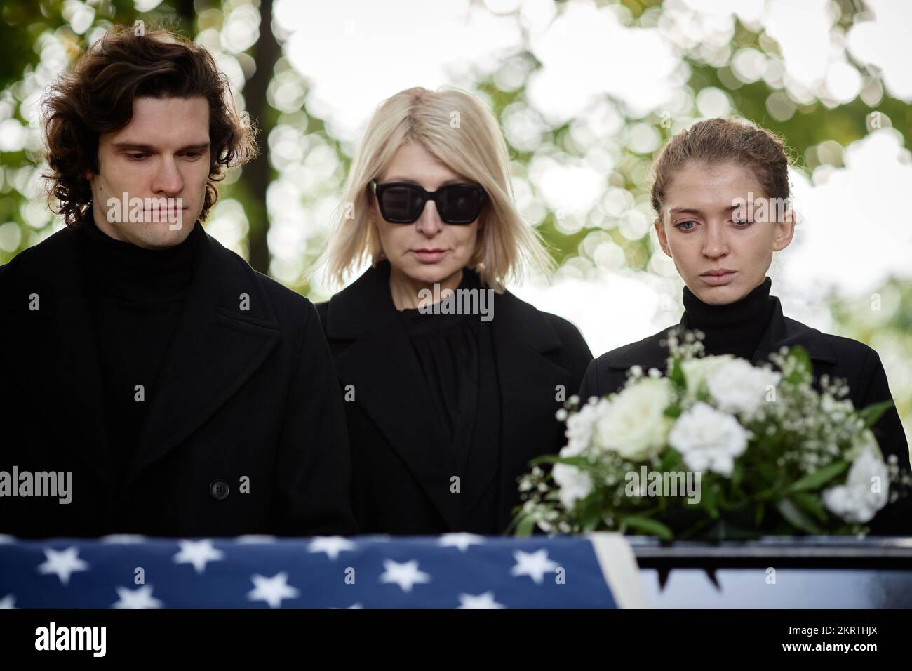 Portrait of family wearing black standing by coffin at outdoor funeral