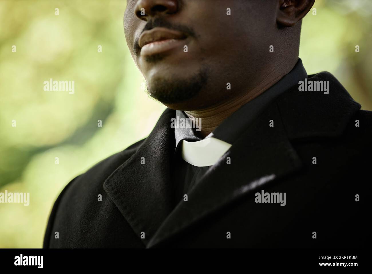 Close up of African American priest wearing black at outdoor funeral ceremony with focus on clerical collar, copy space Stock Photo