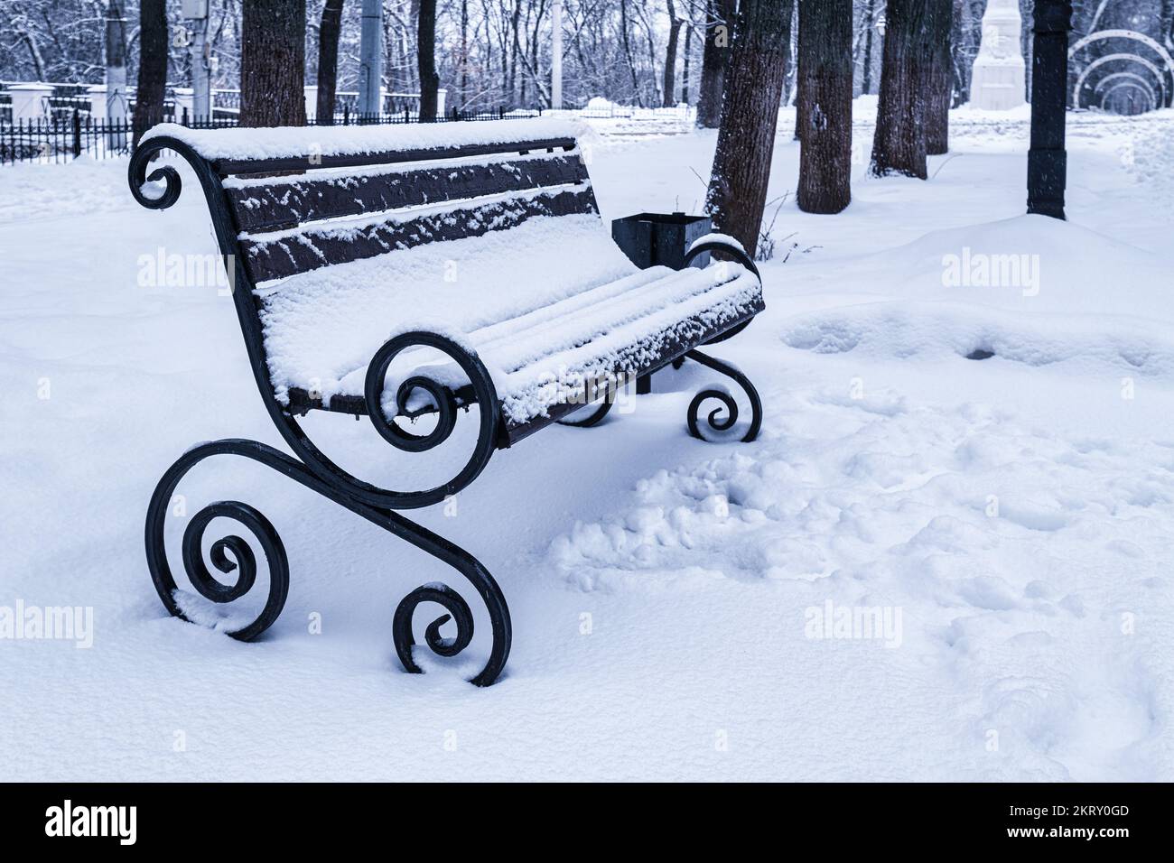 A bench in the park covered with snow in winter. Winter weather and ...