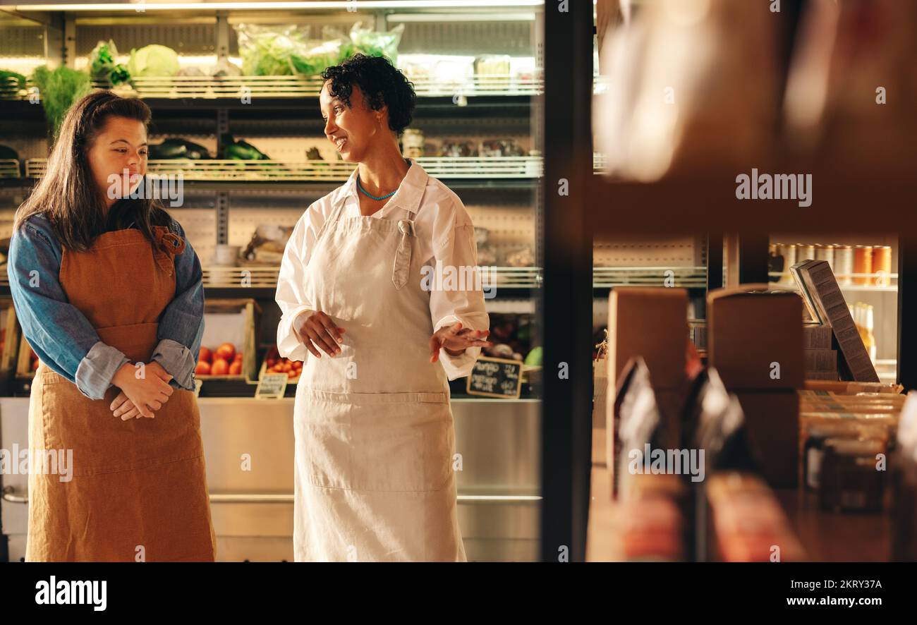 Mature grocery store manager giving instructions to her new employee in