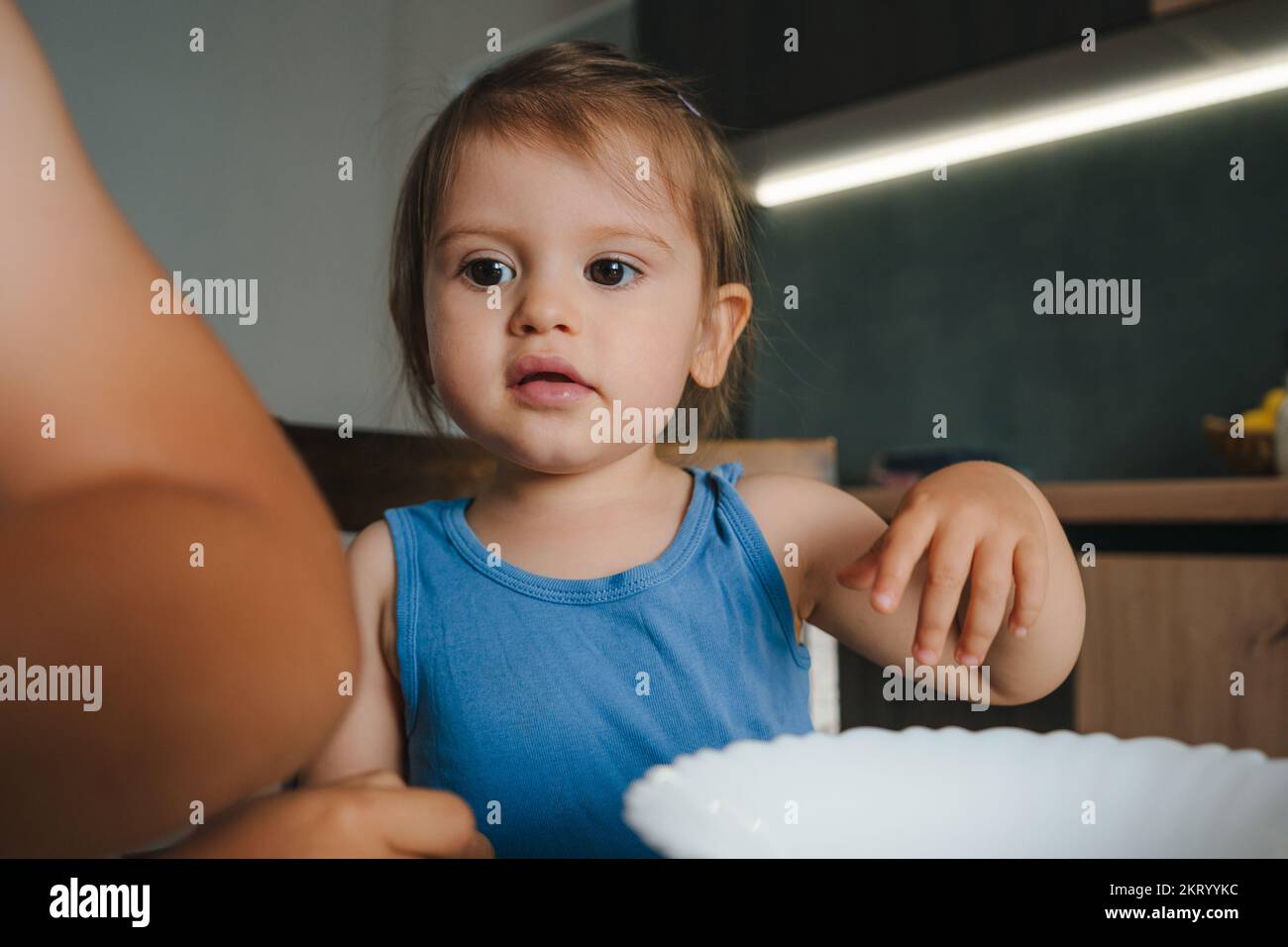 Cute little baby girl helping her mother to make homemade muffins in a