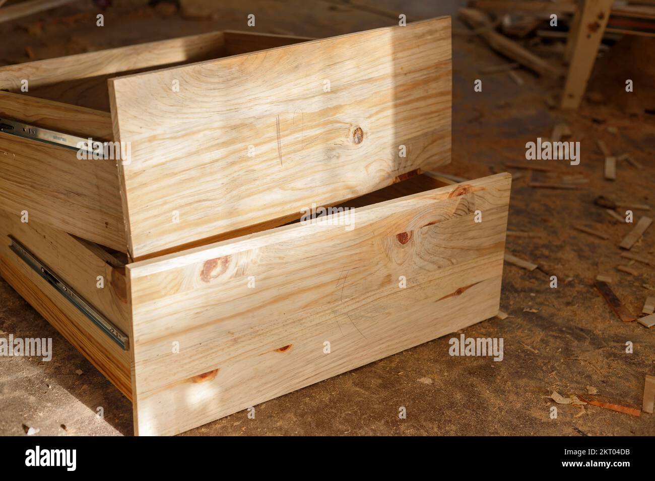 two yellow pine drawers stacked on the floor of a dusty woodwork shop Stock Photo