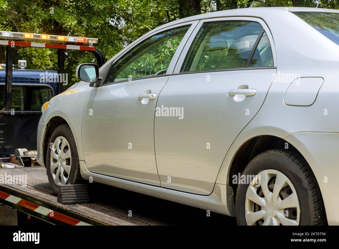 Loading damaged broken car onto tow truck while working for towing