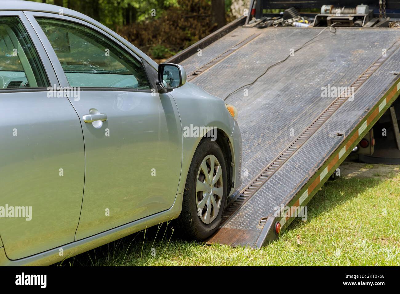 Loading damage broken car on tow truck vehicle working in towing