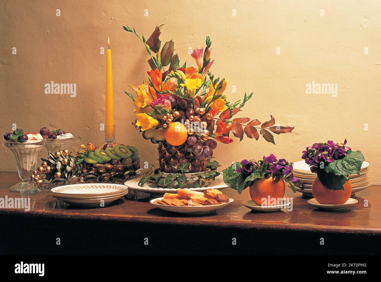 Stylish arrangement of fruit, foliage and flowers on table Stock Photo