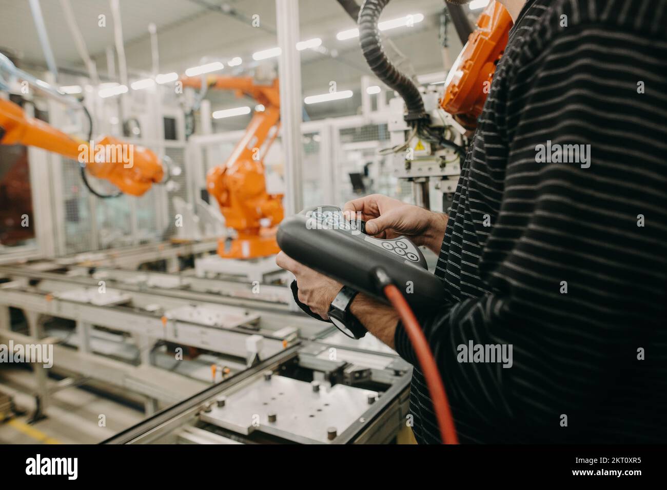 Technical engineer adjusting a robotic arm in the industrial automotive hall, industry concept Stock Photo
