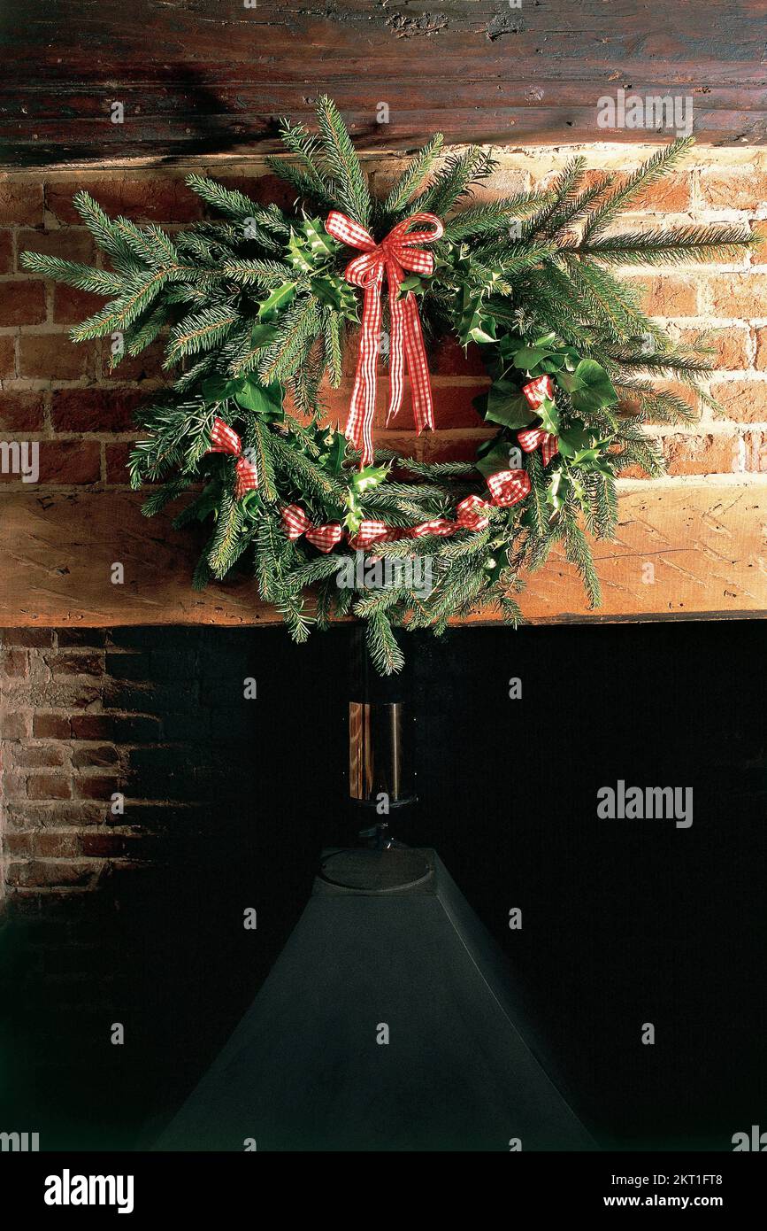 Evergreen wreath hanging over fireplace Stock Photo Alamy