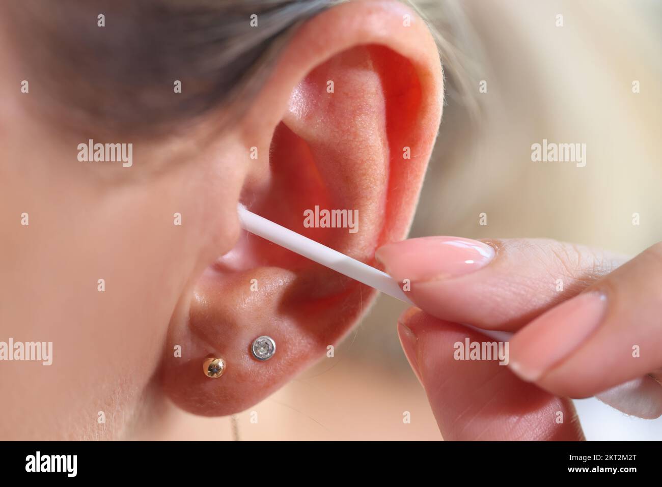 Woman cleaning her ear with cotton swab, people hygiene concept. Stock Photo