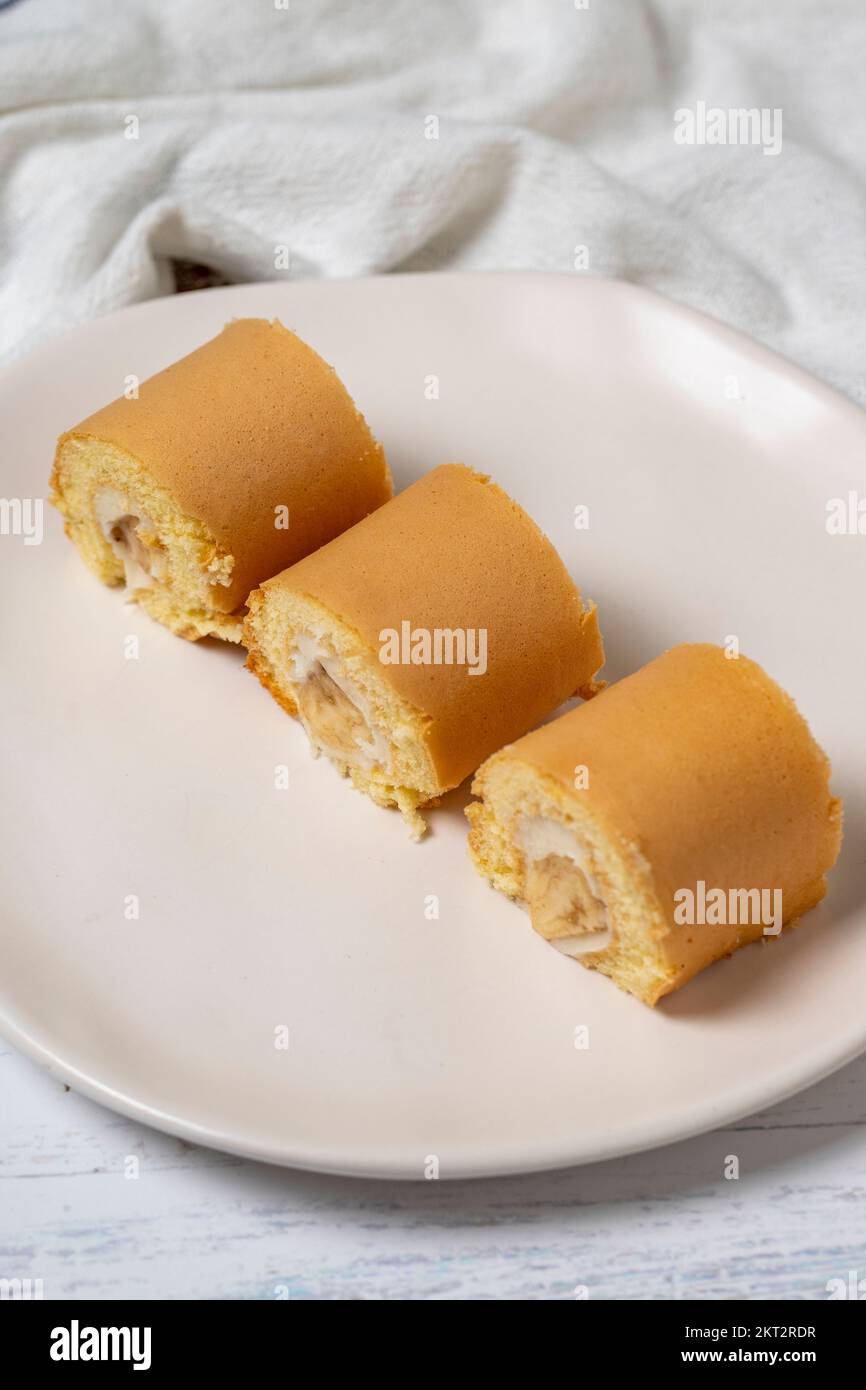 Banana roll cake. Snack roll cake on a white wood background. close up