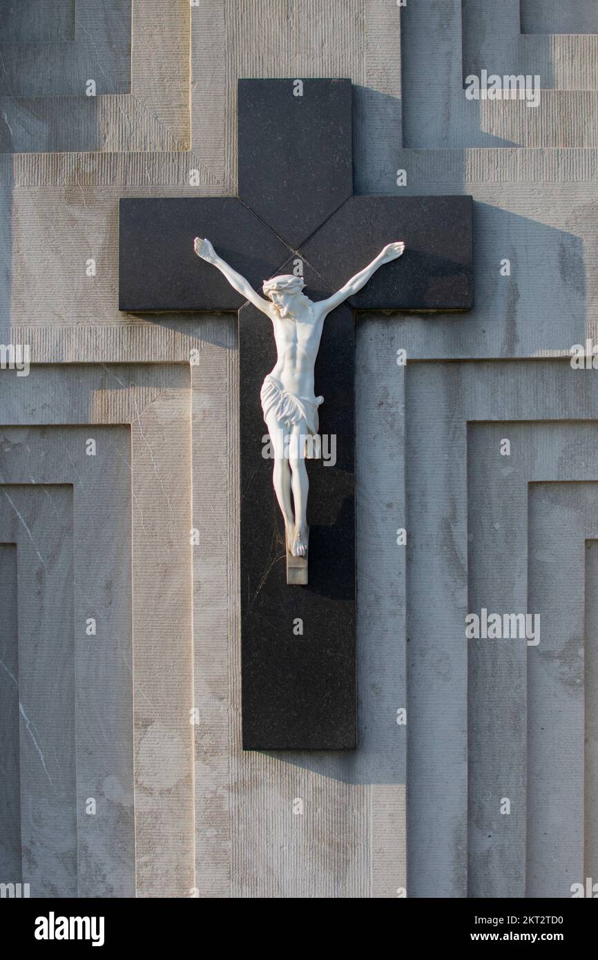 A white statuette of Jesus Christ on a large black cross Stock Photo