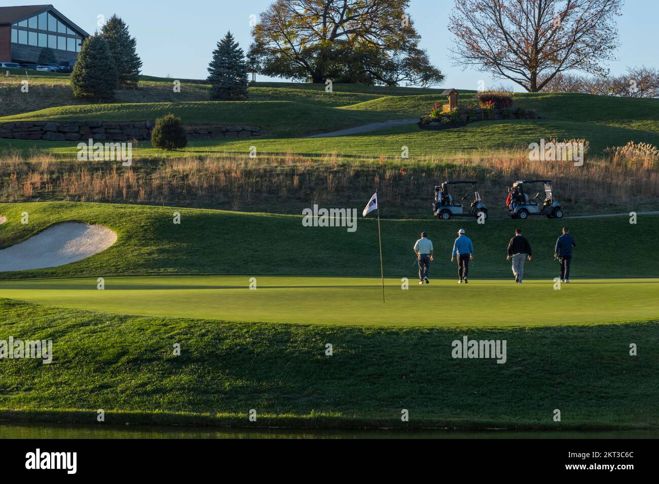Foursome walking away leaving 18th hole after golfing, late afternoon, Pennsylvania, USA Stock Photo