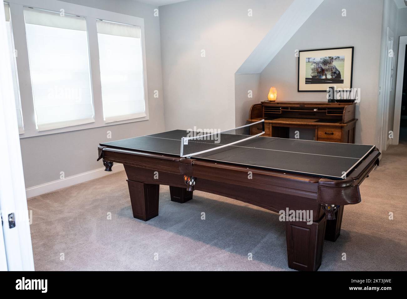A game room or bonus upstairs room with a pool table converted to a table tennis game Stock Photo
