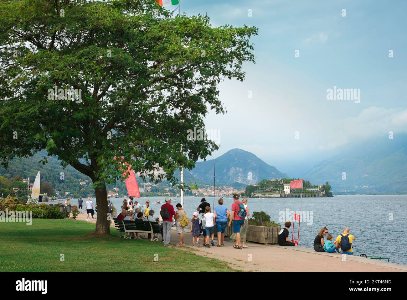 Stresa Lake Maggiore, view in summer of people walking the Passeggiata Lungolago on the Stresa waterfront with Isola Bella visible in the lake, Italy Stock Photo