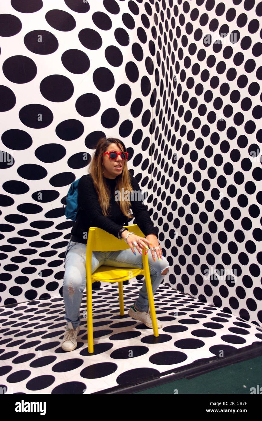 young protagonist posing on yellow chair and black and white psychedelic background in a modern room Stock Photo
