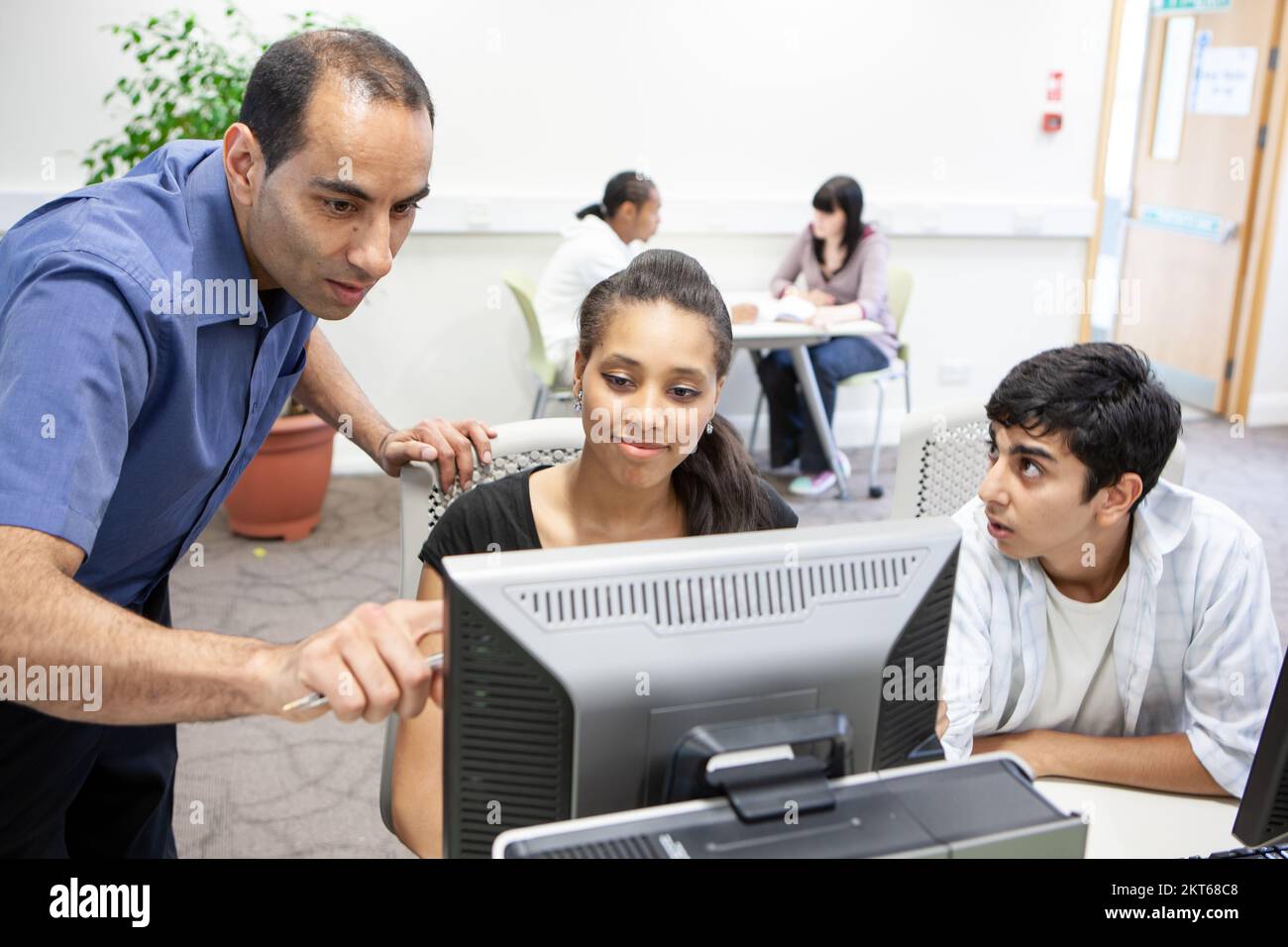 Computer Studies; Online Learning. A teacher helping his late-teenage student understand an academic problem. From a series of related images. Stock Photo