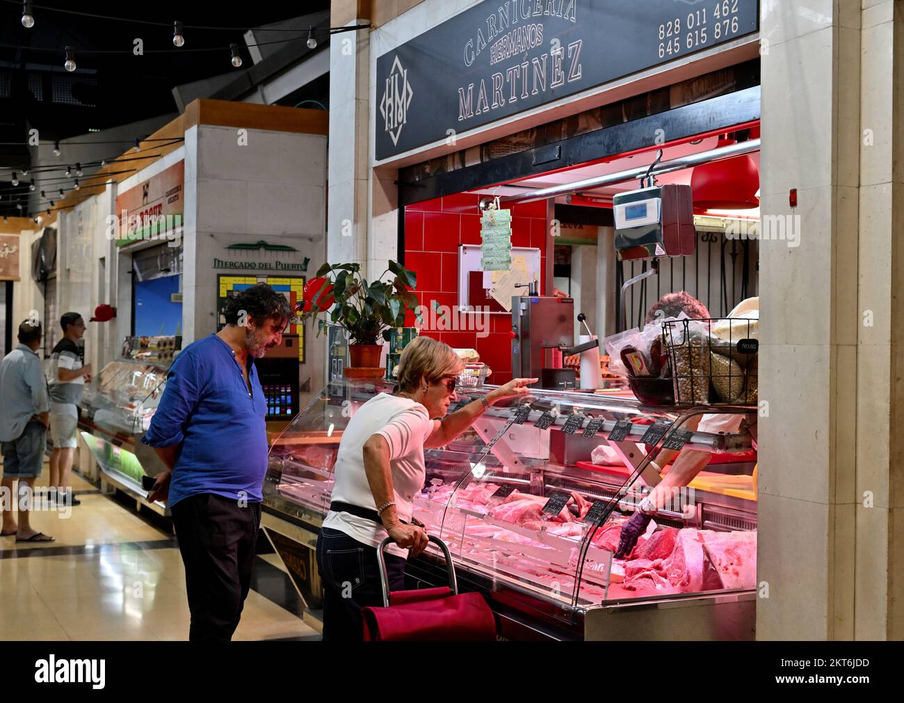 Customers selecting meat at small traditional butchers stall in Mercado