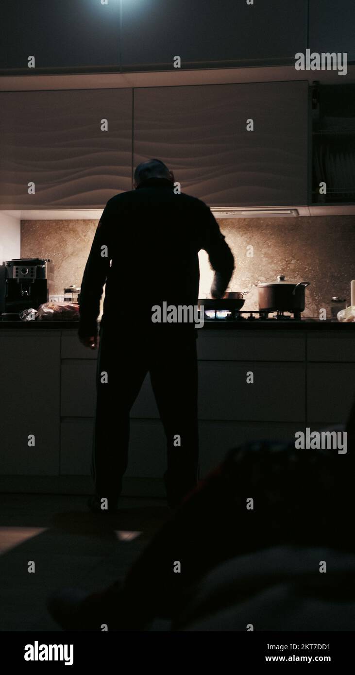 Man cooking with flashlights on a kitchen during blackout in ukraine
