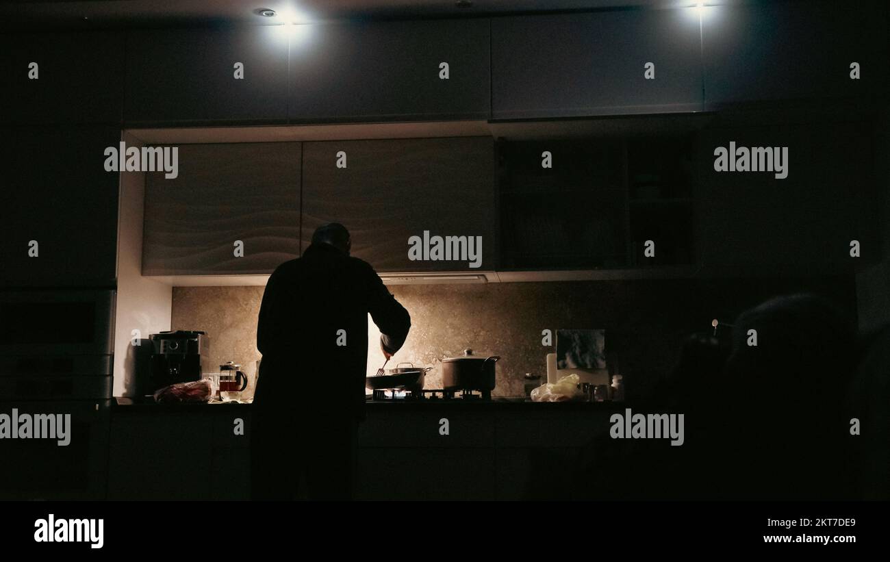Man cooking with flashlights on a kitchen during blackout in ukraine