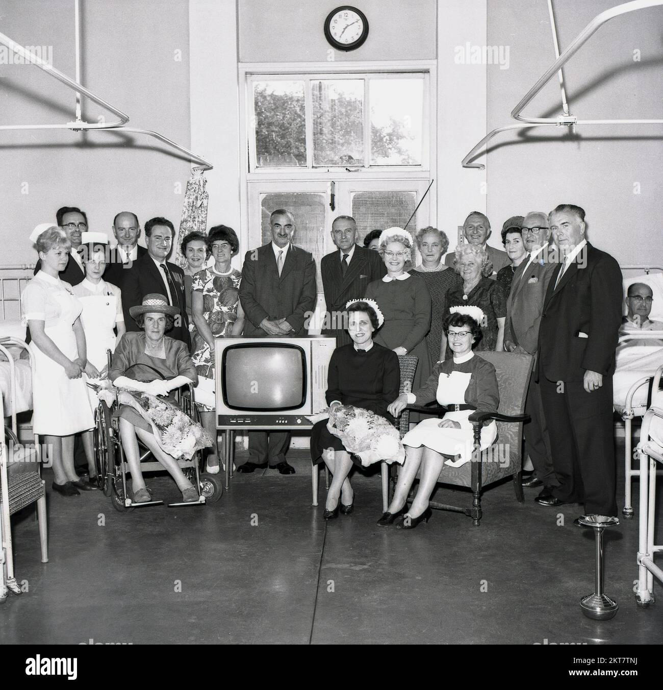 1964, historical, nurses and medical staff gather for a group photo to celebrate a new television set arriving on a hospital ward, England, UK. As televison sets were expensive in this era, it was a major event for hospitals and schools to receive one. Note a stainless steel stand alone ashtray can be seen on the right as in this era, as smoking was still alllowed at certain times on many hospital wards. Stock Photo