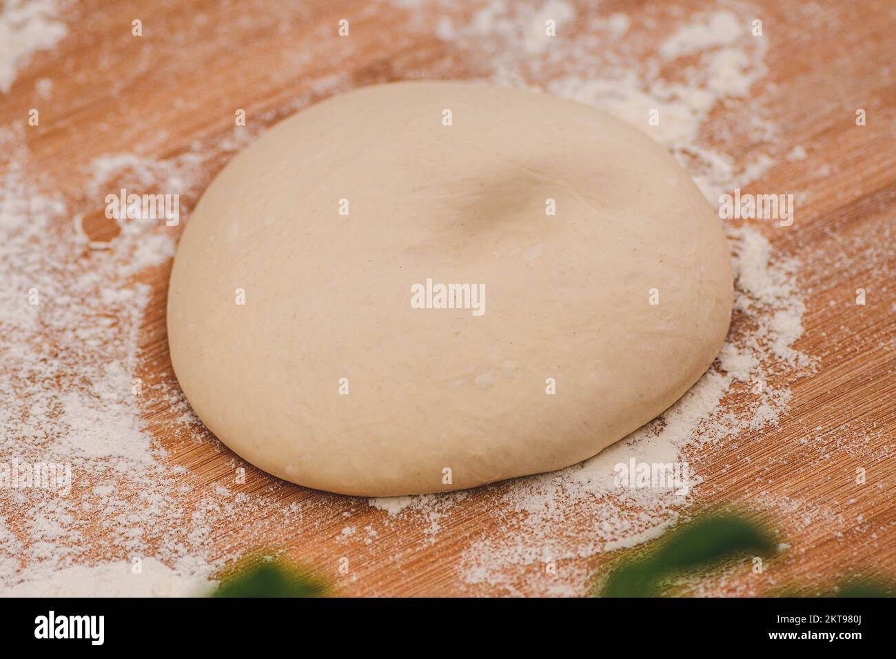 Dough for pizza on a wooden board with white flour and ingredients around ready for preparation, close up Stock Photo